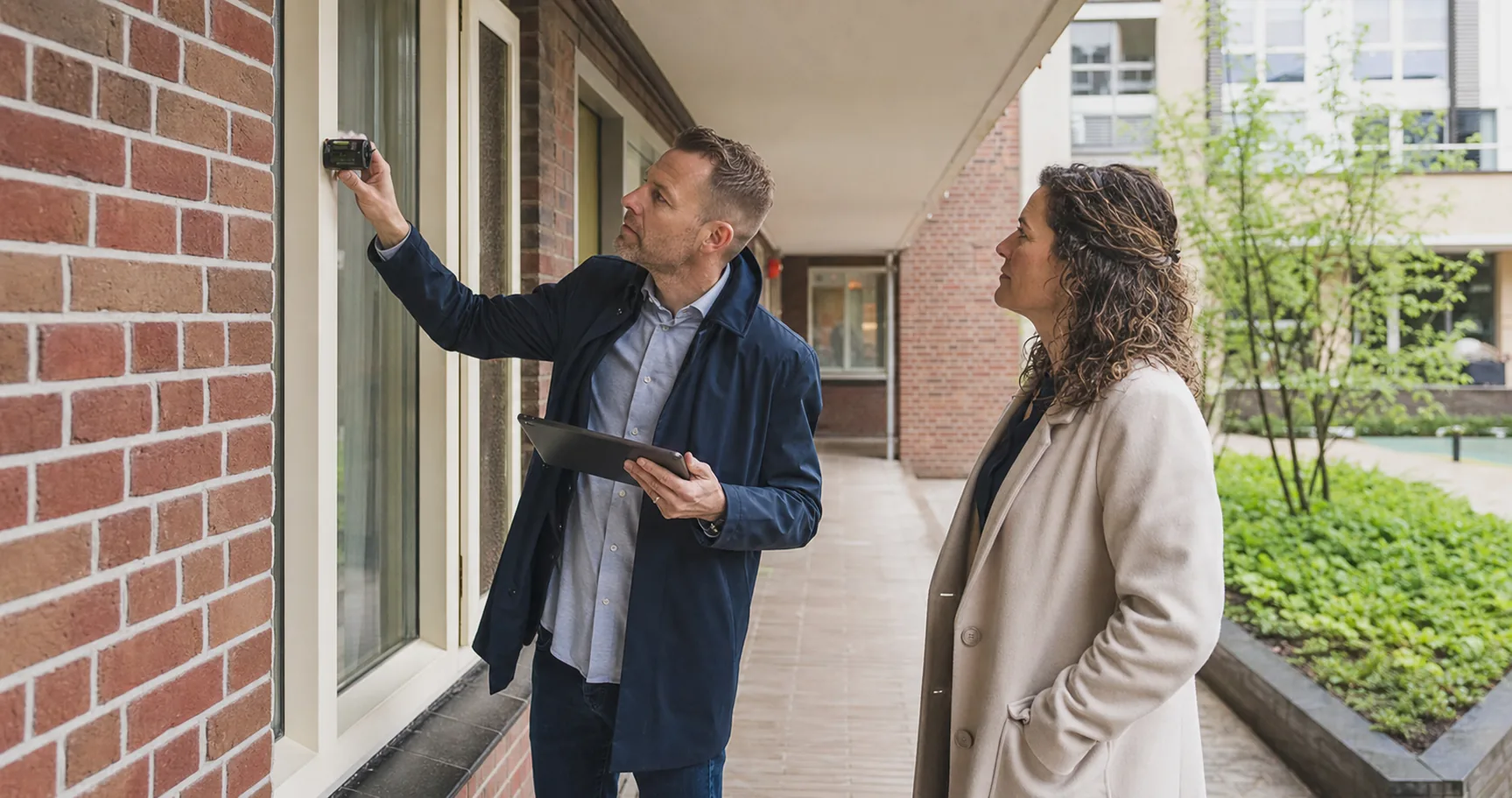 Een energieprestatieadviseur controleert zorgvuldig een kozijn en gevelaansluiting